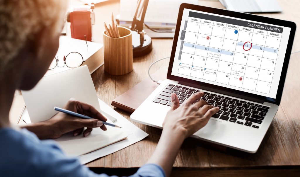 A woman looking at a calendar on a laptop computer.