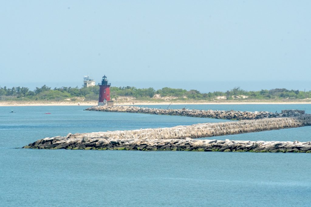 The Breakwater East End Lighthouse in the distance, with the stones of the breakwater zigzagging in the foreground.