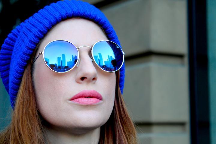 Woman with sunglasses wearing a blue knit beanie